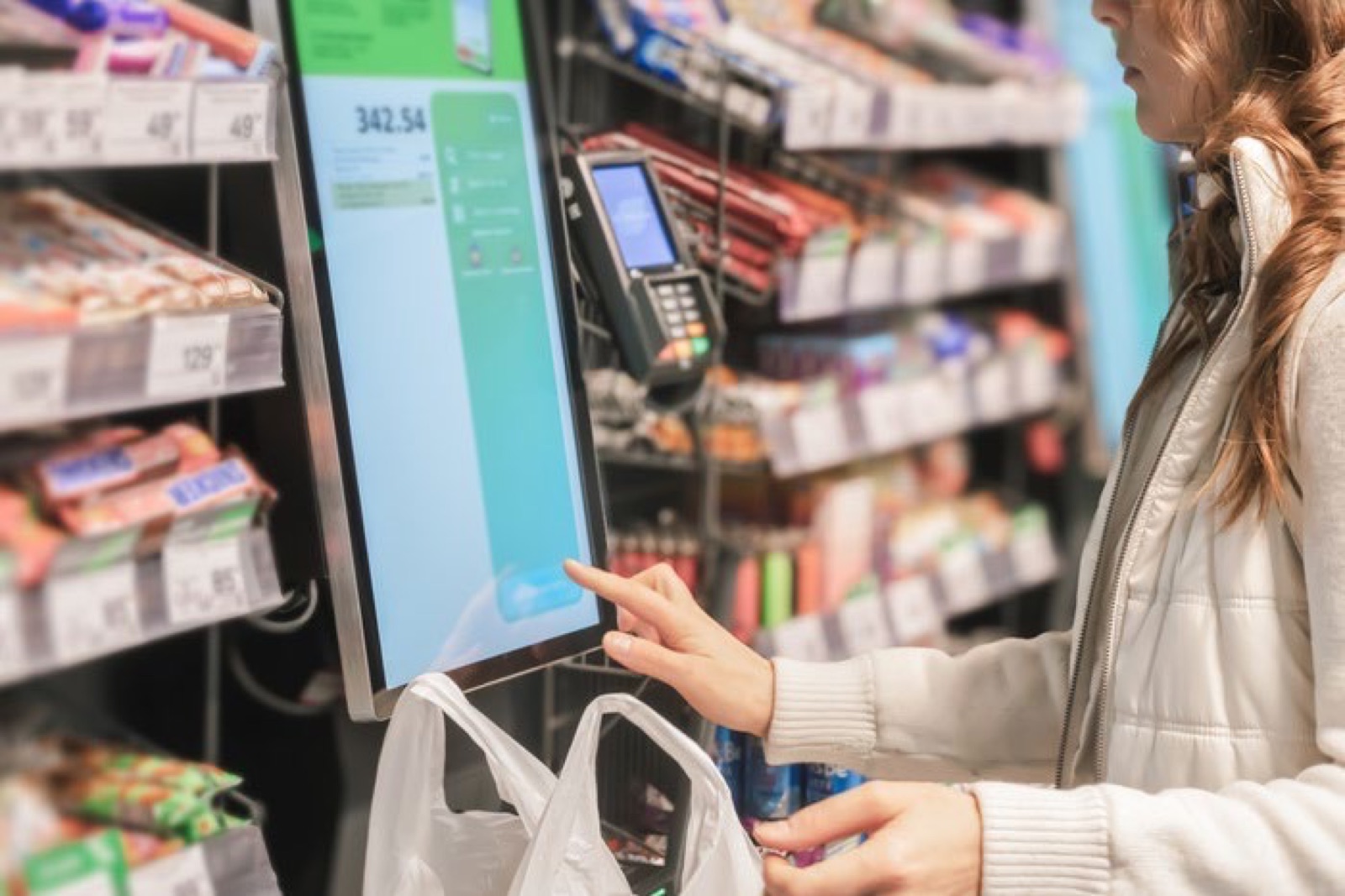 Cliente pagando sozinha no equipamento de autoatendimento de um mercado autônomo
